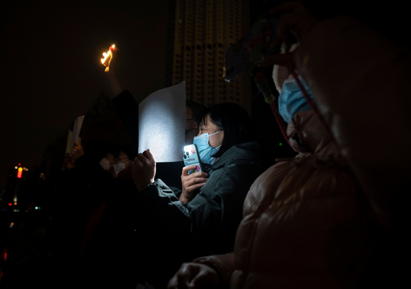 Más participantes en una marcha en Pekín luciendo sus papeles contra la censura