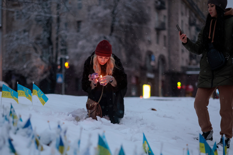Una ciudadana enciende una vela sobre la nieve en Kiev este domingo