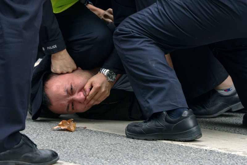 Un hombre es reducido y silenciado por agentes de la policía en una protesta en Shanghai, el pasado domingo.