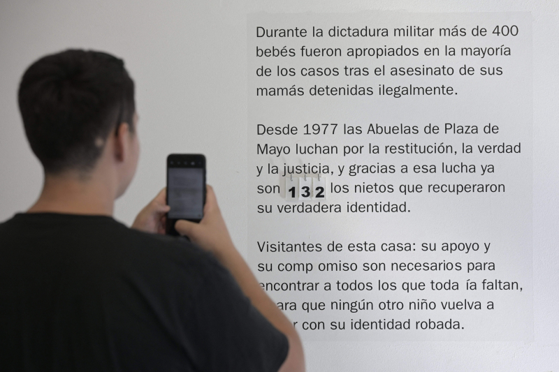 Un joven toma una fotografía de uno de los carteles de las Abuelas de la Plaza de Mayo que narran la historia de Argentina