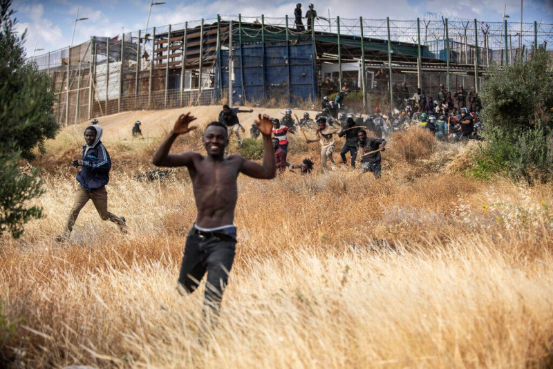 Numerosos migrantes corren hacia el territorio español tras cruzar la valla de Melilla, que separa a España de Marruecos. El 24 de junio de 2022.
