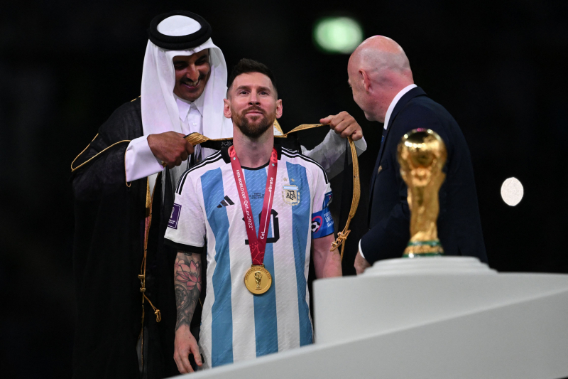 El emir de Qatar, el jeque Tamim bin Hamad Al Thani, coloca una capa o 'bisht' a Lionel Messi tras ganar la selección argentina el Mundial de Fútbol de Qatar, el 18 de diciembre de 2022. 