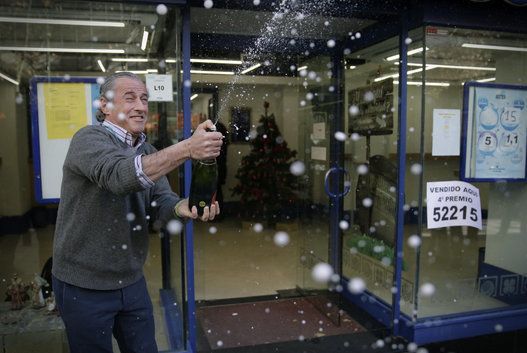 The owner of the lottery administration at Calle Orense, 50, in Madrid, celebrates the sale of number 52215, fourth prize in the extraordinary Christmas Lottery draw.