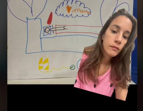 Una madre enseña el dibujo que ha hecho de ella su hijo en el colegio